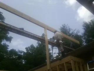 Carpenter setting a ridge beam over a new addition frame — Ice Dam Removal by Roofing Brothers in Bagley