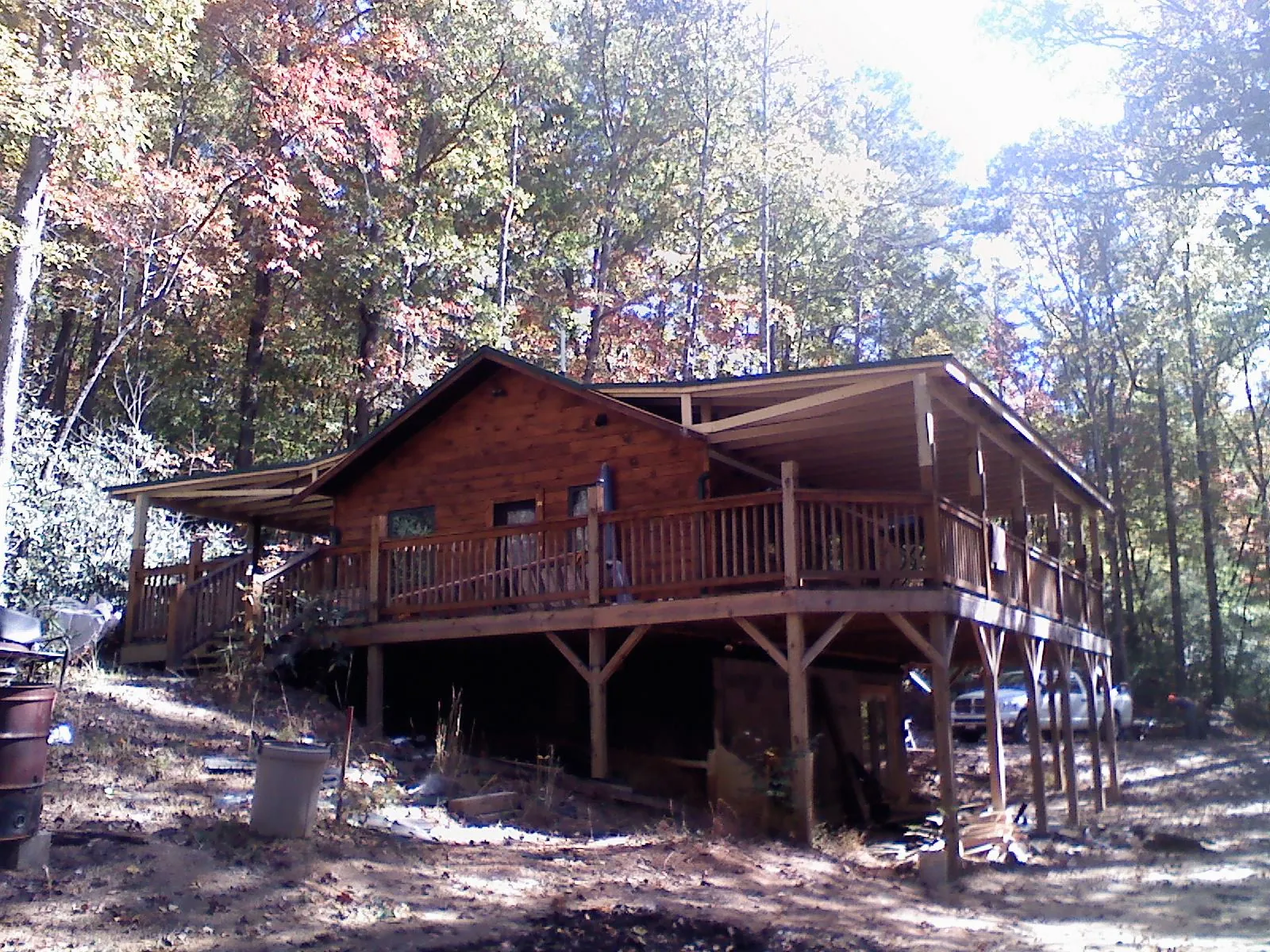Log cabin with a wraparound porch and metal roof in the fall in Bagley