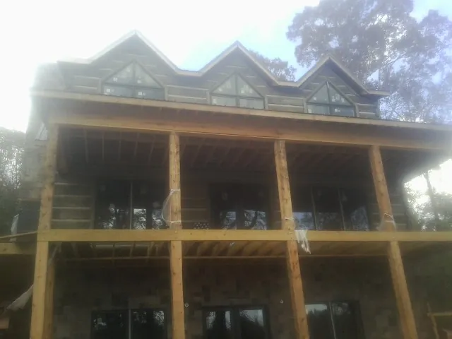 Dormers and porch framing on a large log home under construction — Roof Coating work by our crew in Bagley