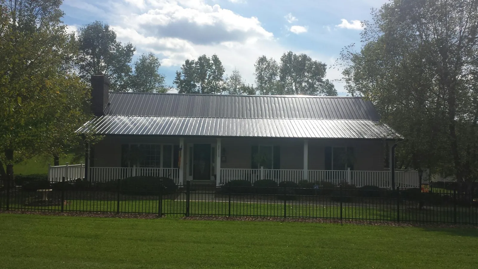 Gray metal roof on a brick ranch with a full width front porch — Gutter Guard Installation work by our crew in Bagley