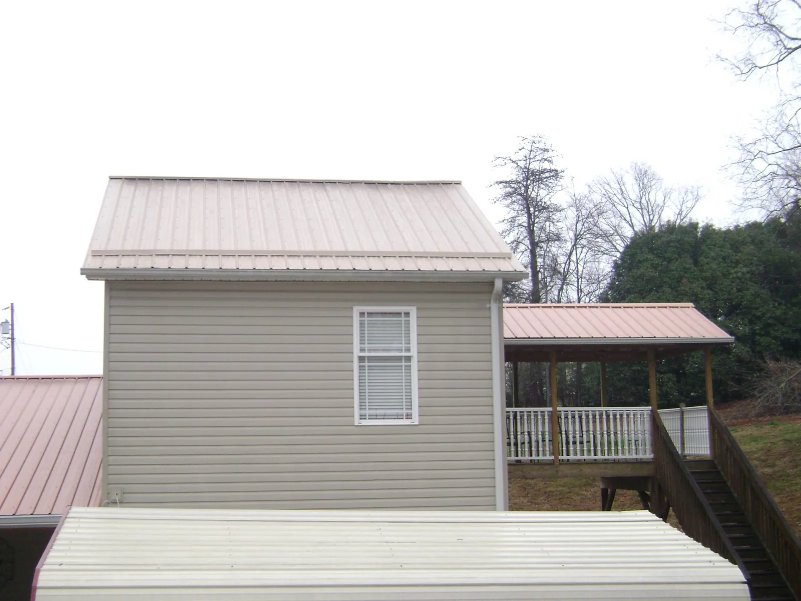 Tan metal roofs on a two story addition and attached porch, from a Roof Replacement job in Bagley